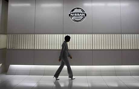 Una empleada pasa junto a un logo de Nissan en la sede de Tokio. | Reuters