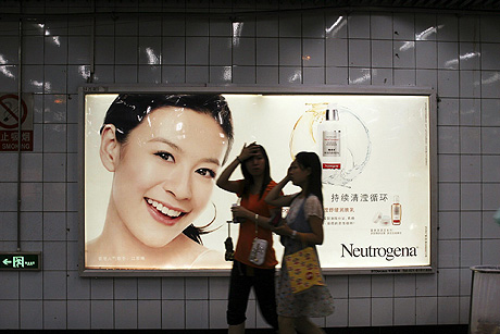 Dos jvenes caminan delante de un anuncio de productos cosmticos en el metro de Shanghai. | Aritz Parra