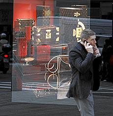 Un hombre hablando por el mvil pasa junto un escaparate de la tienda de lujo de Louis Vuitton, en Valencia. | Jos Cuellar