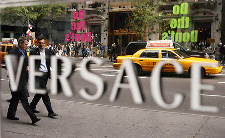 Dos personas caminan junto a la tienda de Versace en la Quinta Avenida de Nueva York. | Reuters