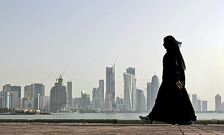 Una mujer camina frente al 'skyline' de Doha, la capital de Qatar. | Ap