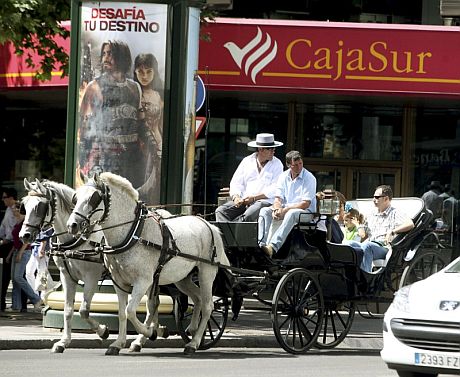 Varios turistas pasean en un coche de caballos ante una de la sede de Cajasur. | Efe