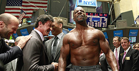 Protagonistas de 'Los mercenarios' en la Bolsa de Nueva York. (De izda. a dcha.) Jason Statham, Sylvester Stallone y Doph Lundgren se ren ante los movimientos de culturismo de Terry Crews.| Reuters