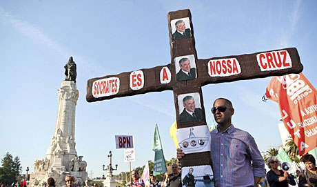 Un hombre sostiene una cruz contra el primer ministro luso durante la manifestacin. | Efe
