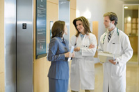 Una comercial charla con dos médicos en un centro sanitario. (Foto: Rick Gómez | Corbis)