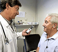 Un médico y un paciente emplean un sistema de traducción simultánea a través del móvil durante una consulta. (Foto: EL MUNDO)